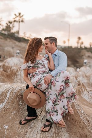 Romantic couple photography session on textured coastal rocks during golden hour.