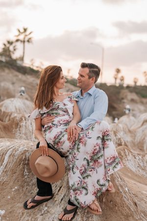 Intimate portrait session featuring couple against sunset-lit coastal landscape.