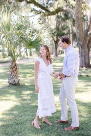 Couple walking together on grass lawn with palm trees and Spanish moss in background.