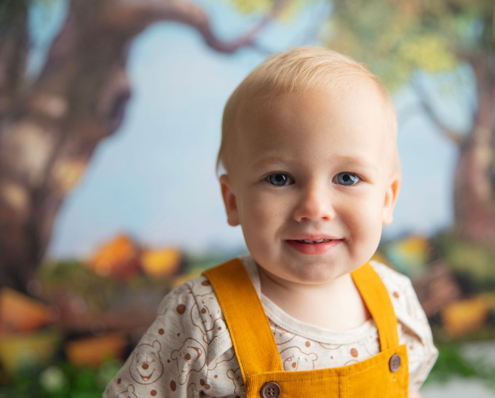 Close-up portrait of a smiling baby with blue eyes in a Winnie the Pooh themed photo session.