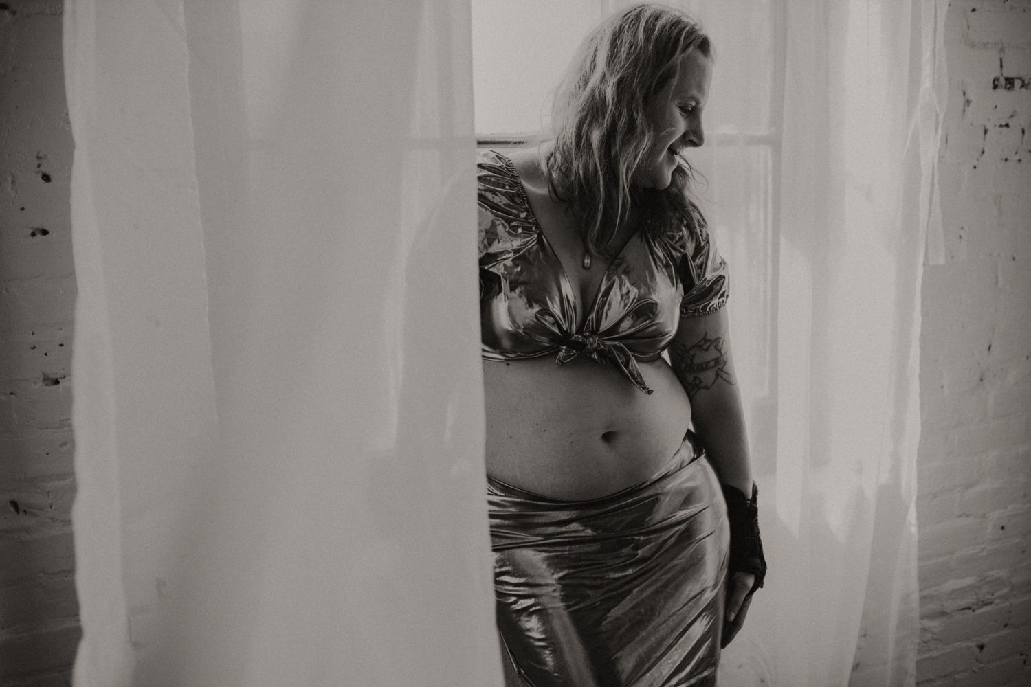 Artistic black and white silhouette photo of person in casual clothing by window.