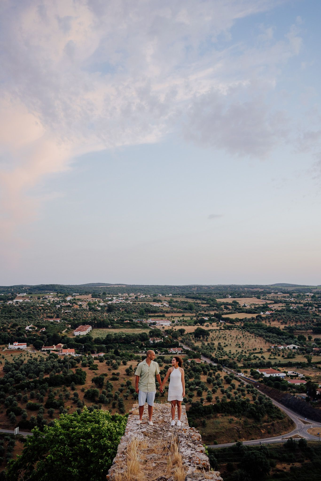 Panoramic view of a rural landscape with rolling hills and scattered houses at dusk.