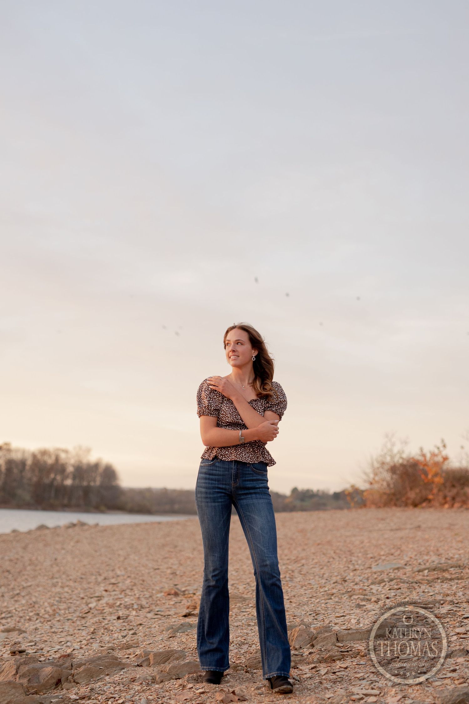 Sunset portrait session on a rocky beach with warm golden lighting.