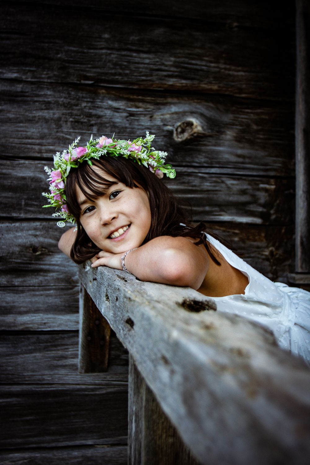 Artistic portrait with floral crown against rustic wooden background.
