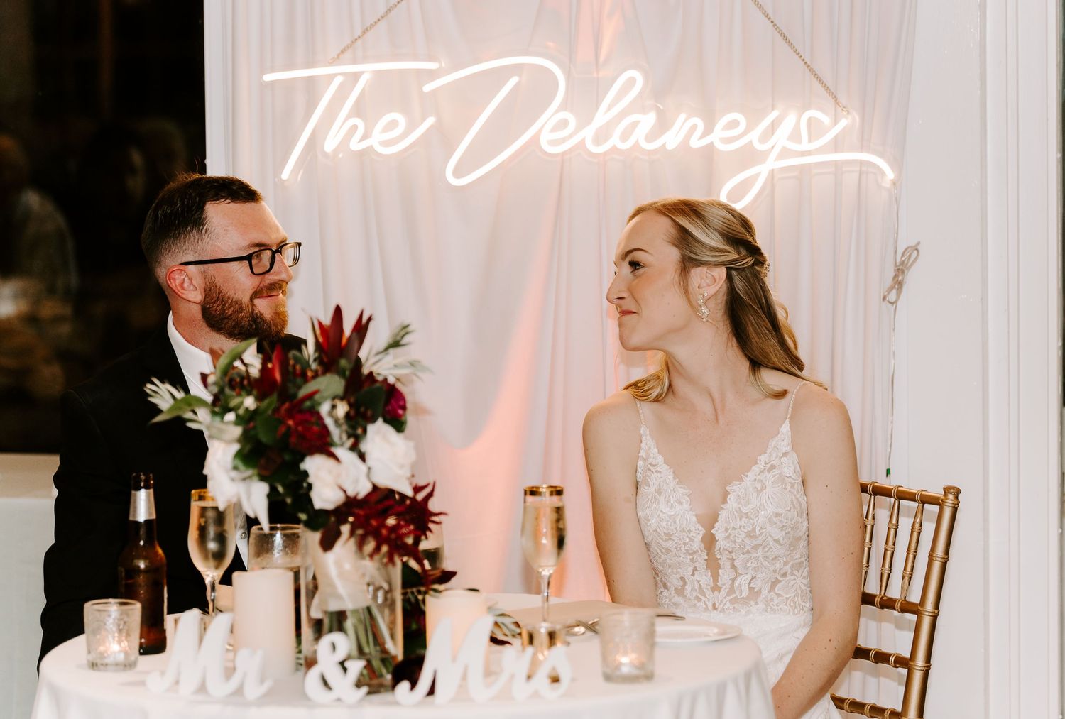 Elegant wedding reception setup with white draping and illuminated name display.