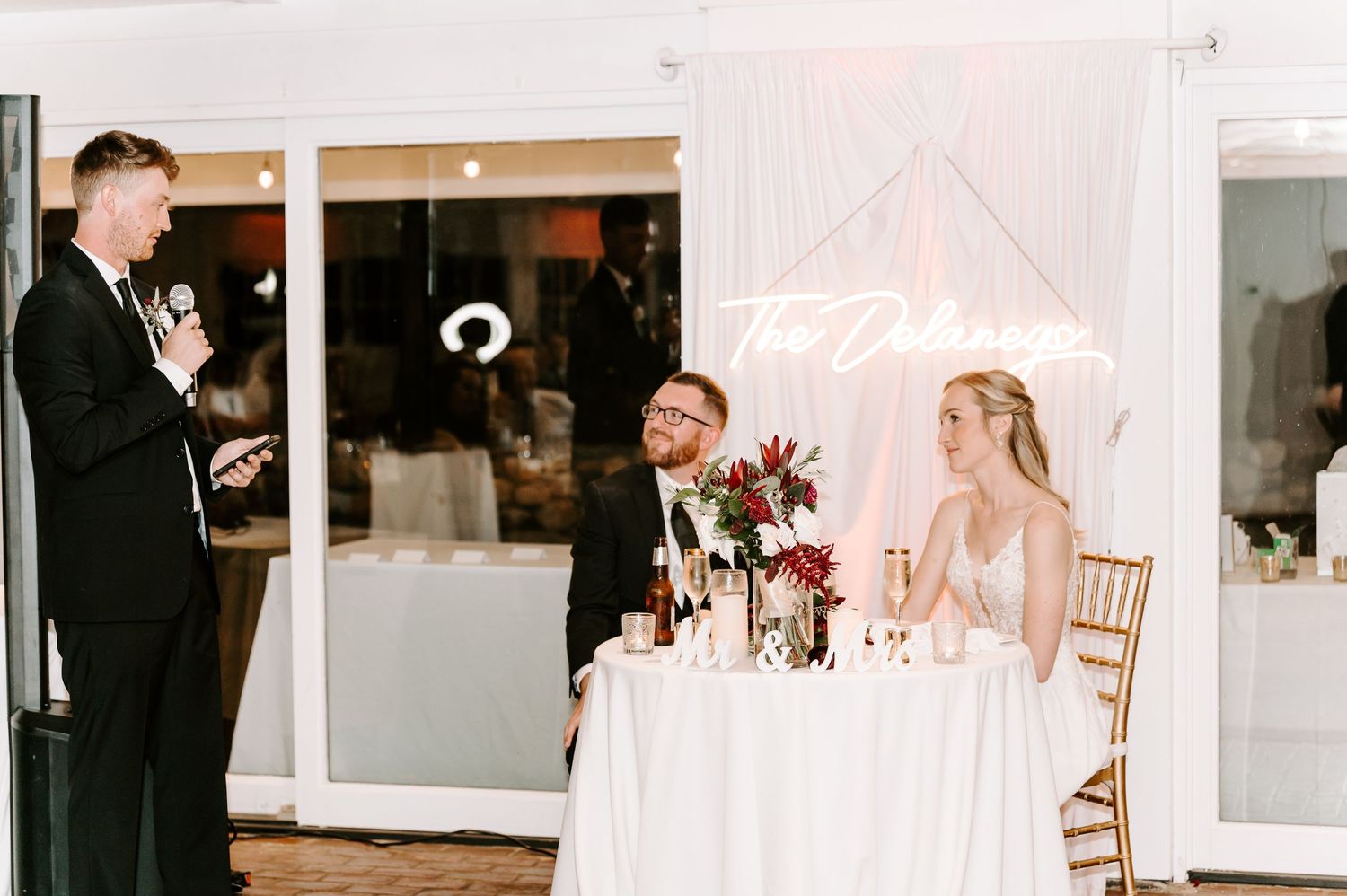 Wedding reception detail showing white draping and illuminated name sign.