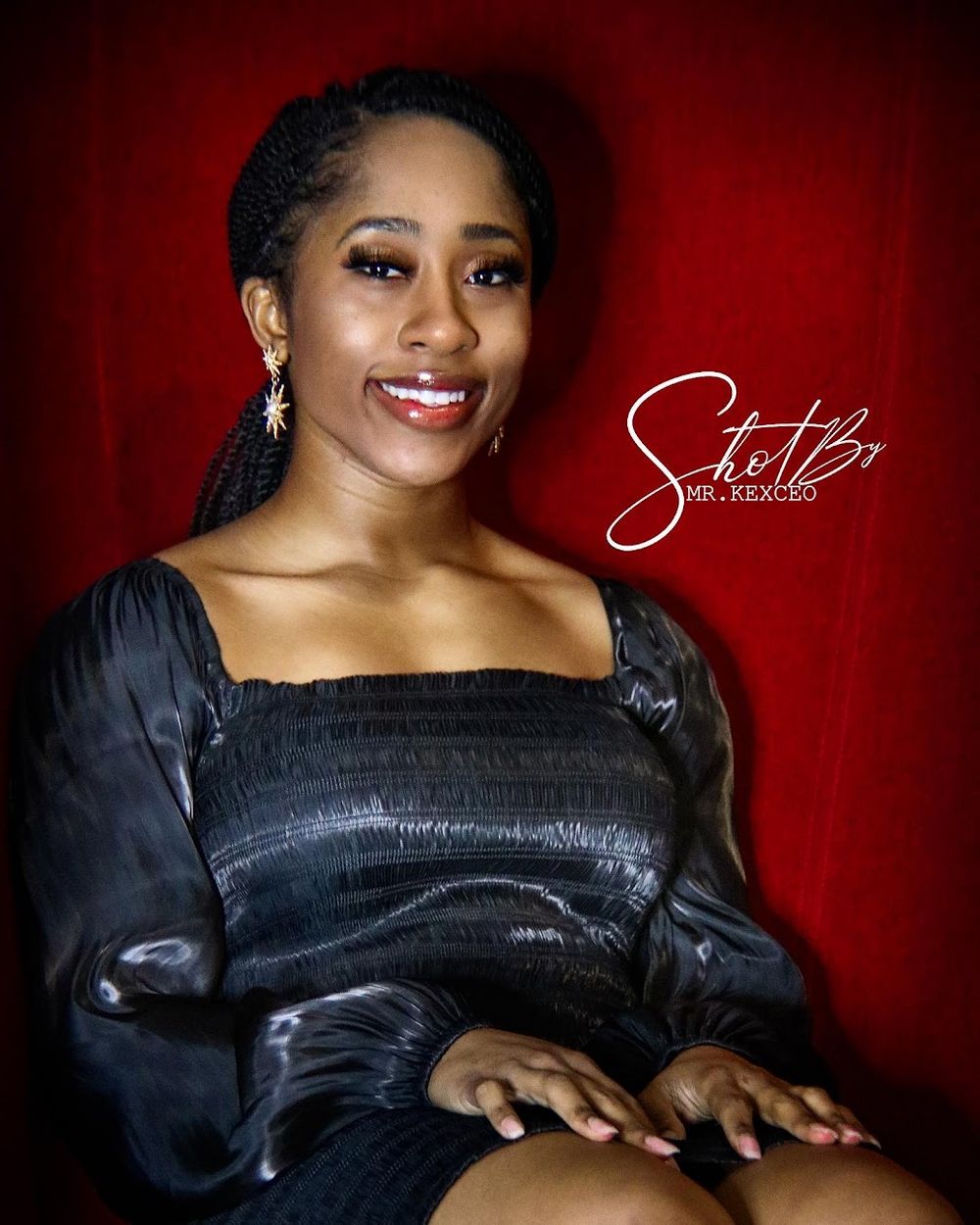 Glamour portrait series against deep red backdrop wearing black dress.