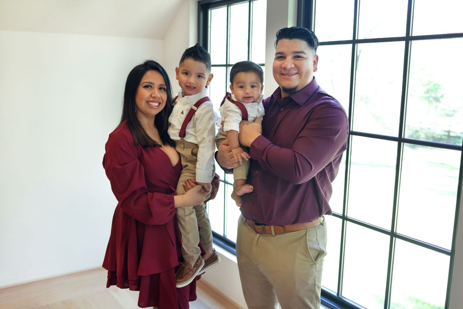 Young family poses together in a bright indoor setting wearing coordinated outfits.