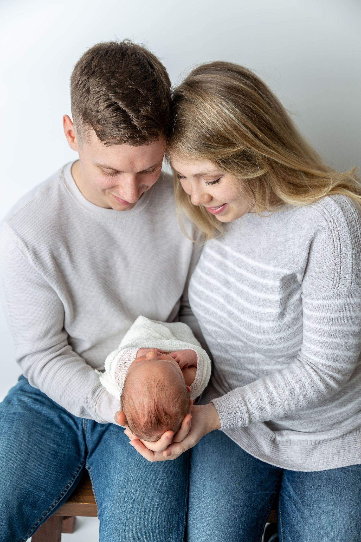 Intimate family moment with newborn baby in soft grey sweaters.