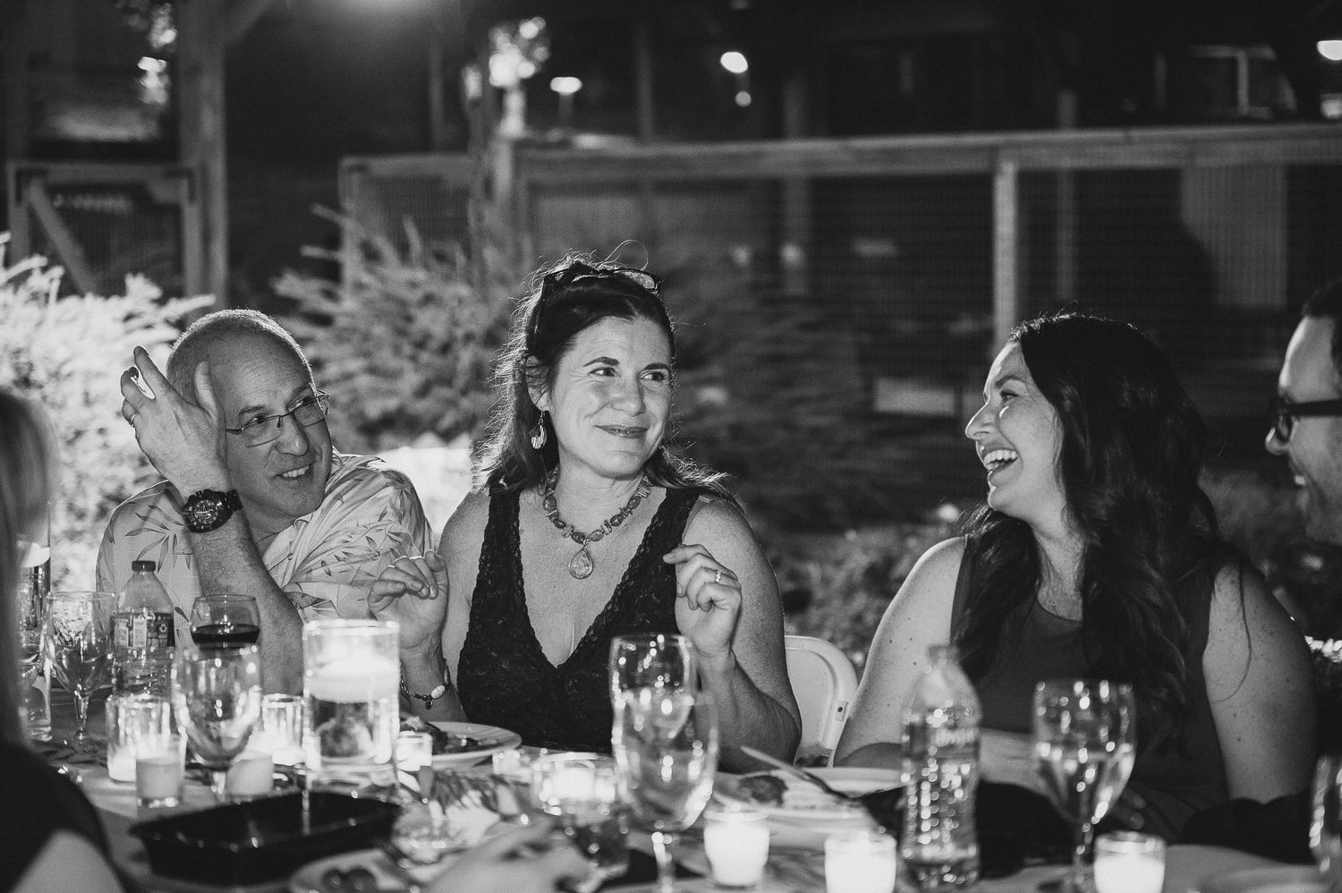 Evening reception gathering with guests enjoying conversation at outdoor tables.