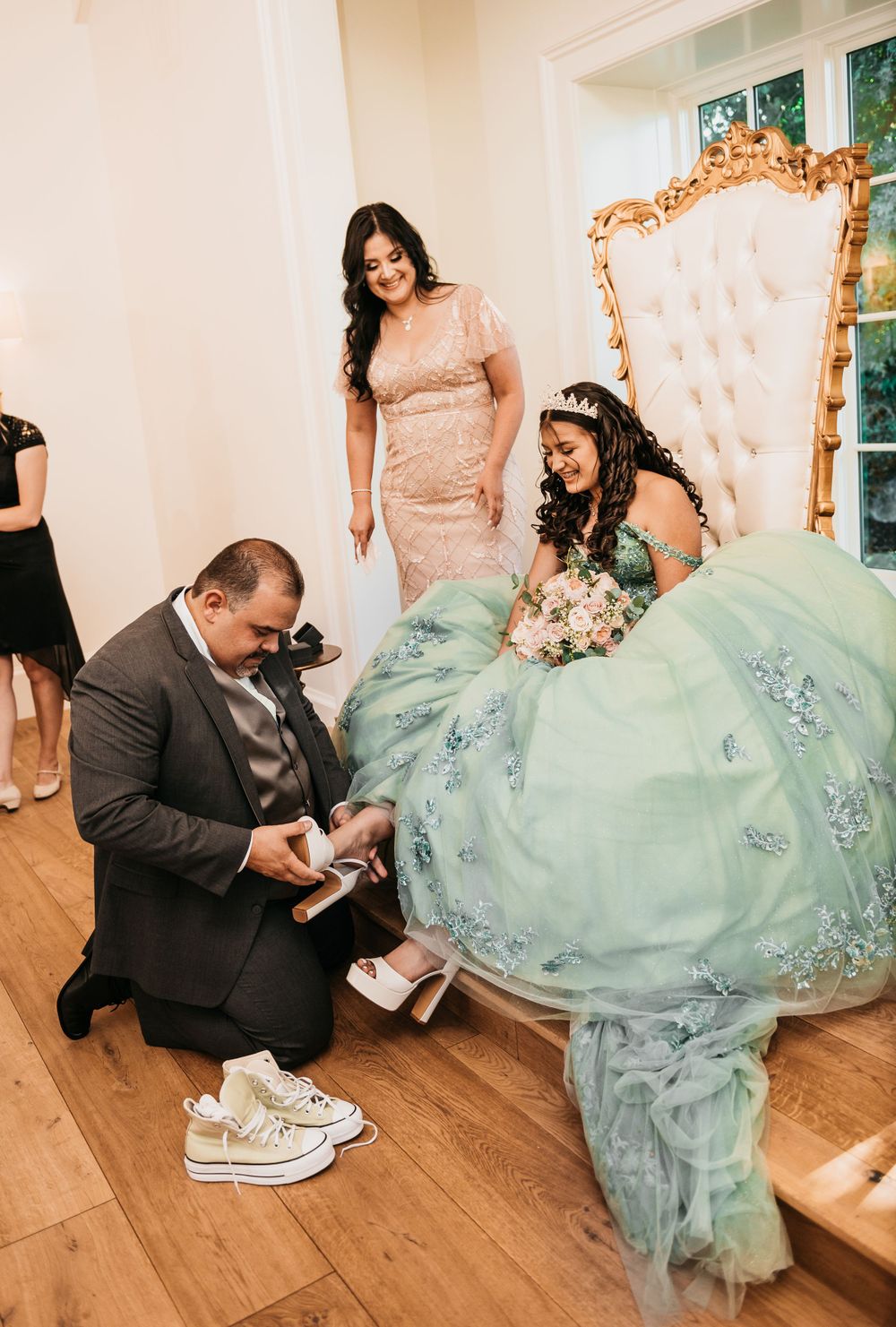 Traditional shoe changing ceremony during quinceañera celebration with mint ballgown.