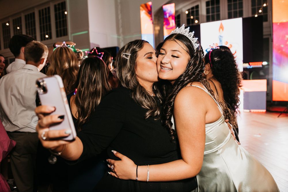 Two celebrants share an intimate friendly moment while dancing at a festive party.