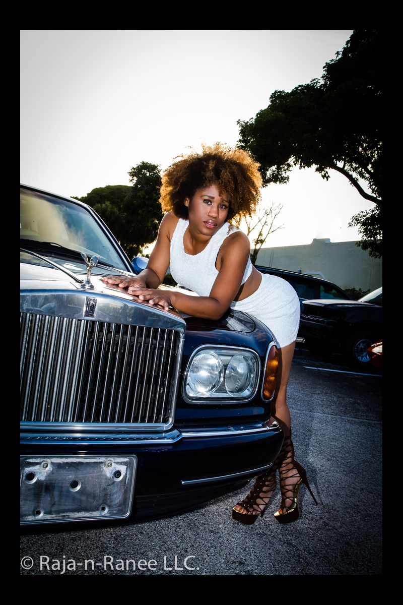 A person in summer attire poses on a Rolls Royce with gladiator sandals.
