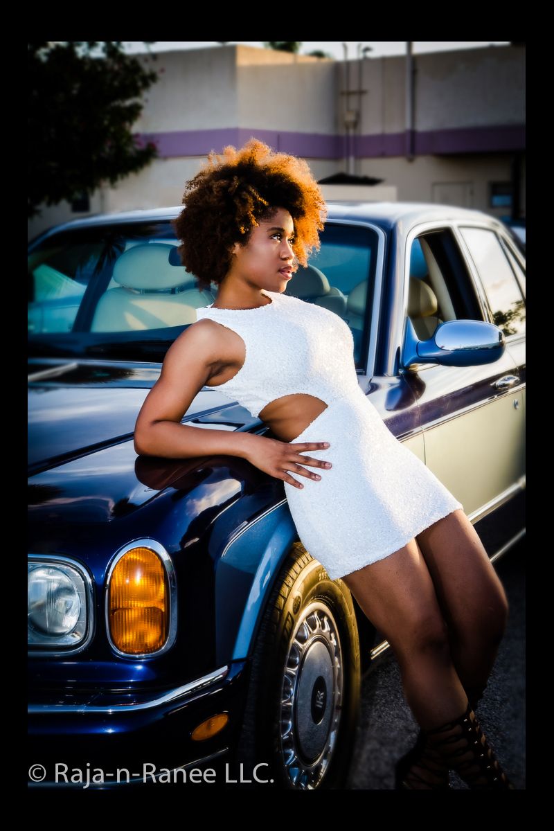 Fashion photography featuring a white dress against a vintage car with amber headlights.