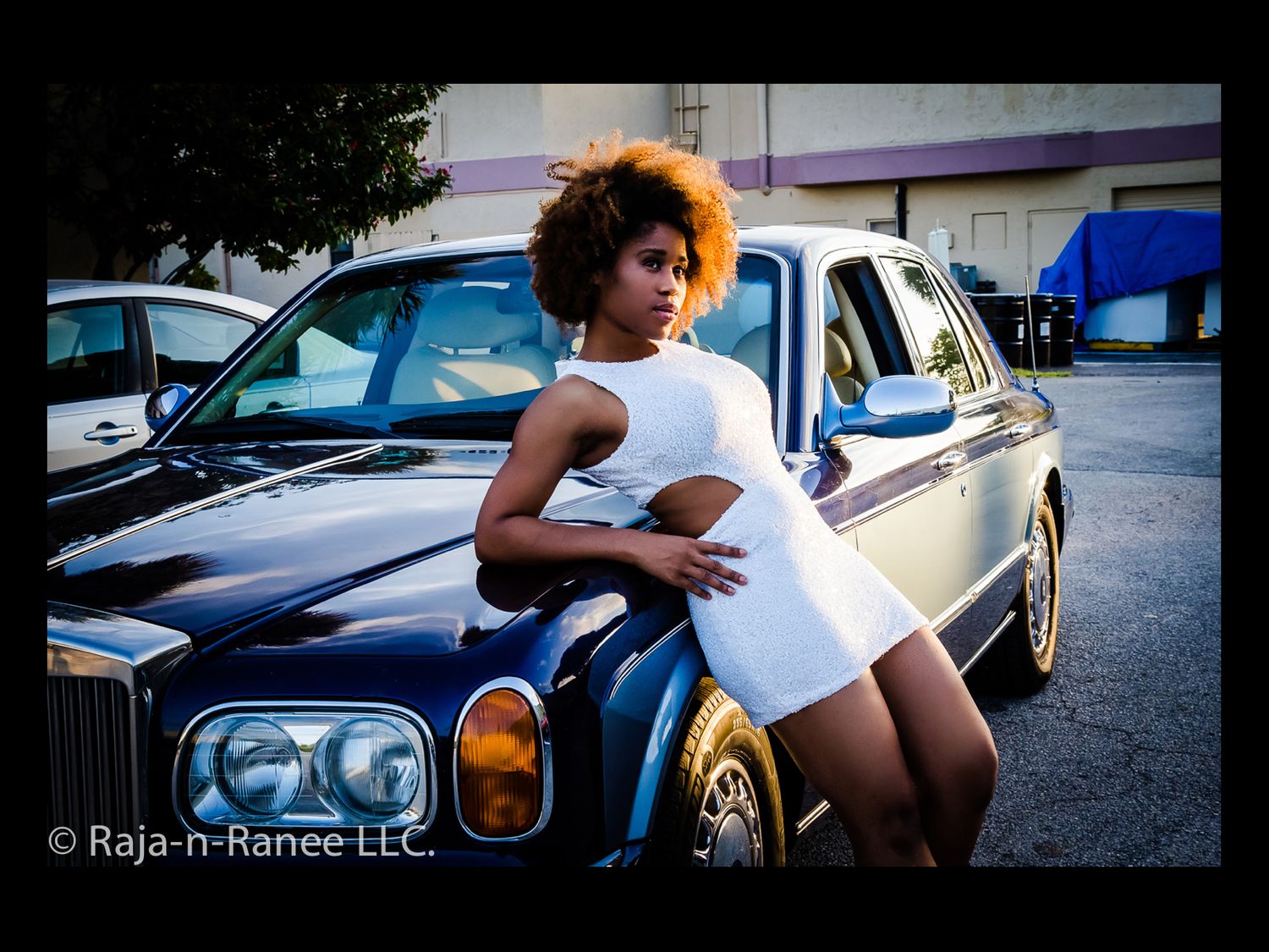Fashion photography session with a classic car in an urban setting during sunset.
