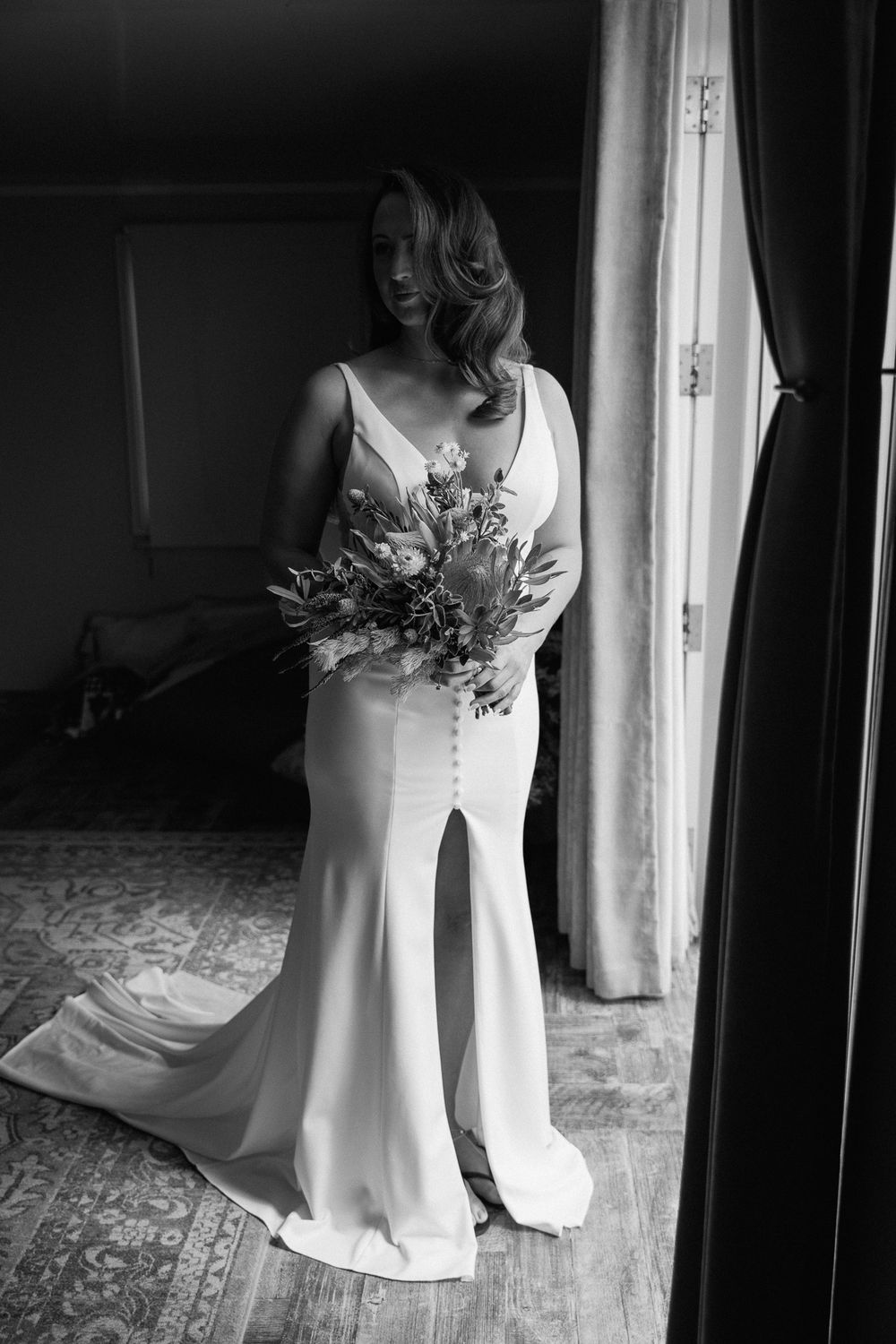 Black and white bridal portrait showing an elegant fitted wedding gown and bouquet.