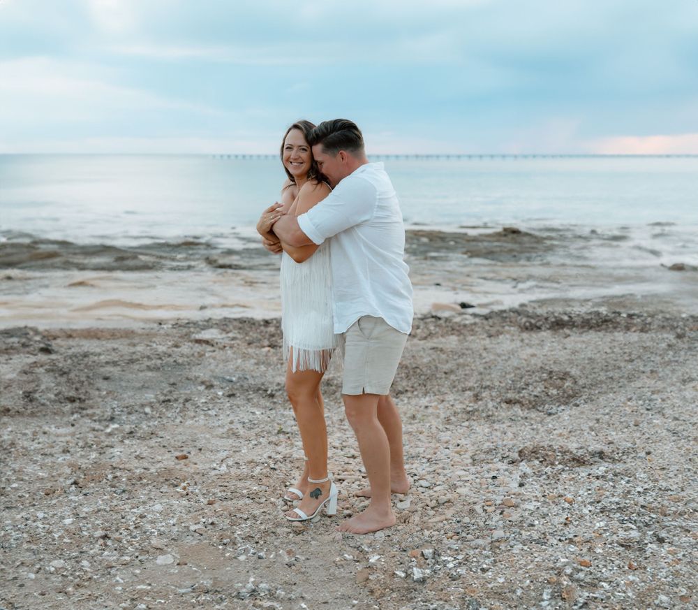 Romantic moment between couple on a pebble beach with ocean waves in background.