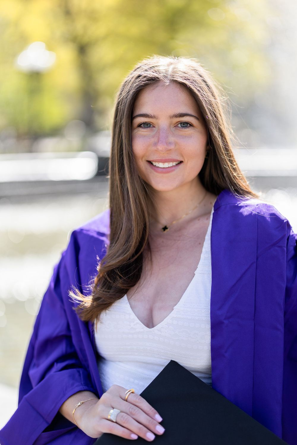 Portrait of graduate wearing purple academic regalia holding black diploma case.