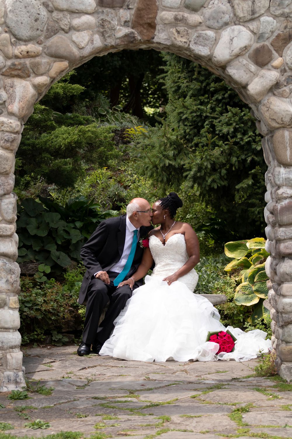 Bride and groom framed inside a stone archway kissing