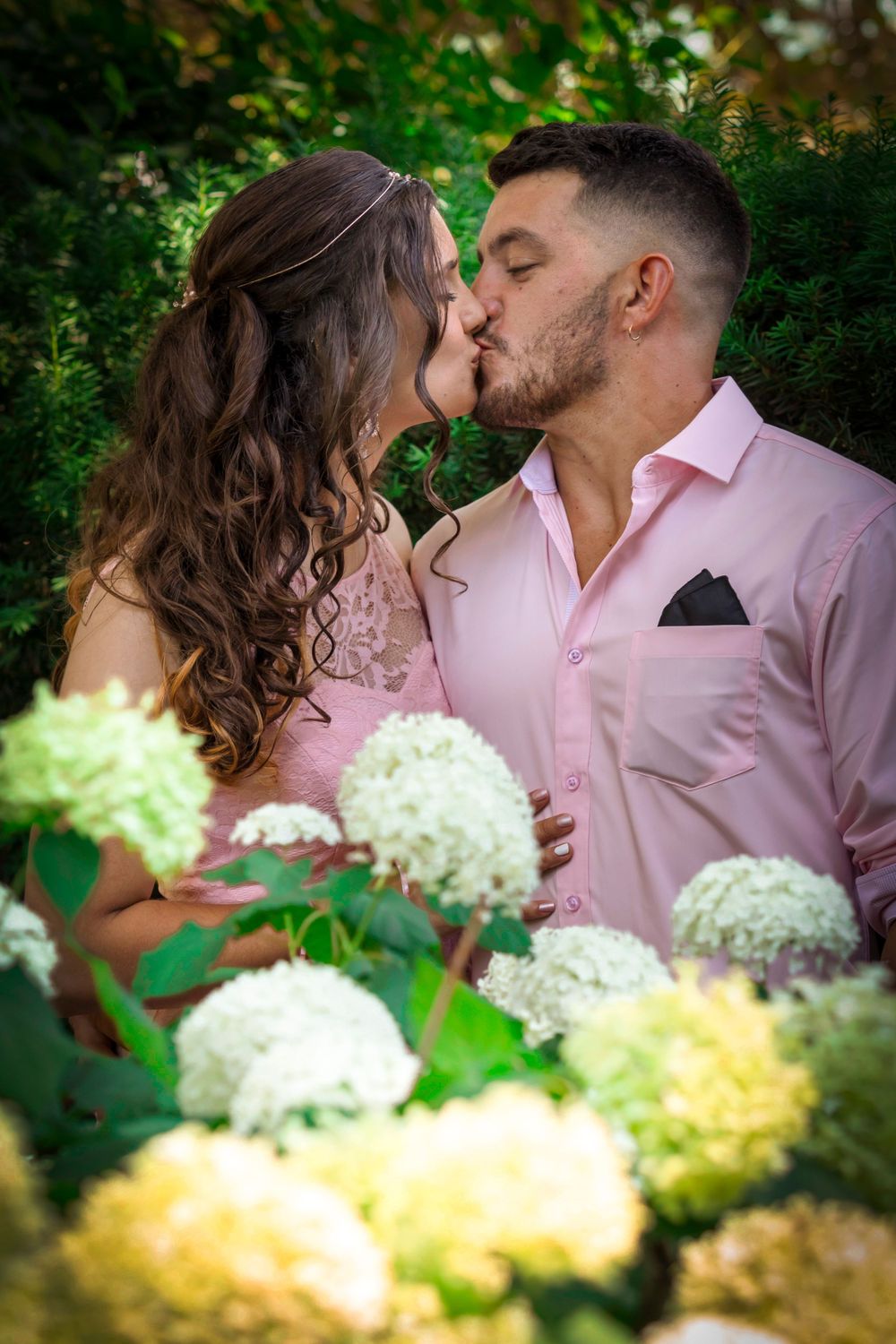 Bride and groom kissing behind peonies