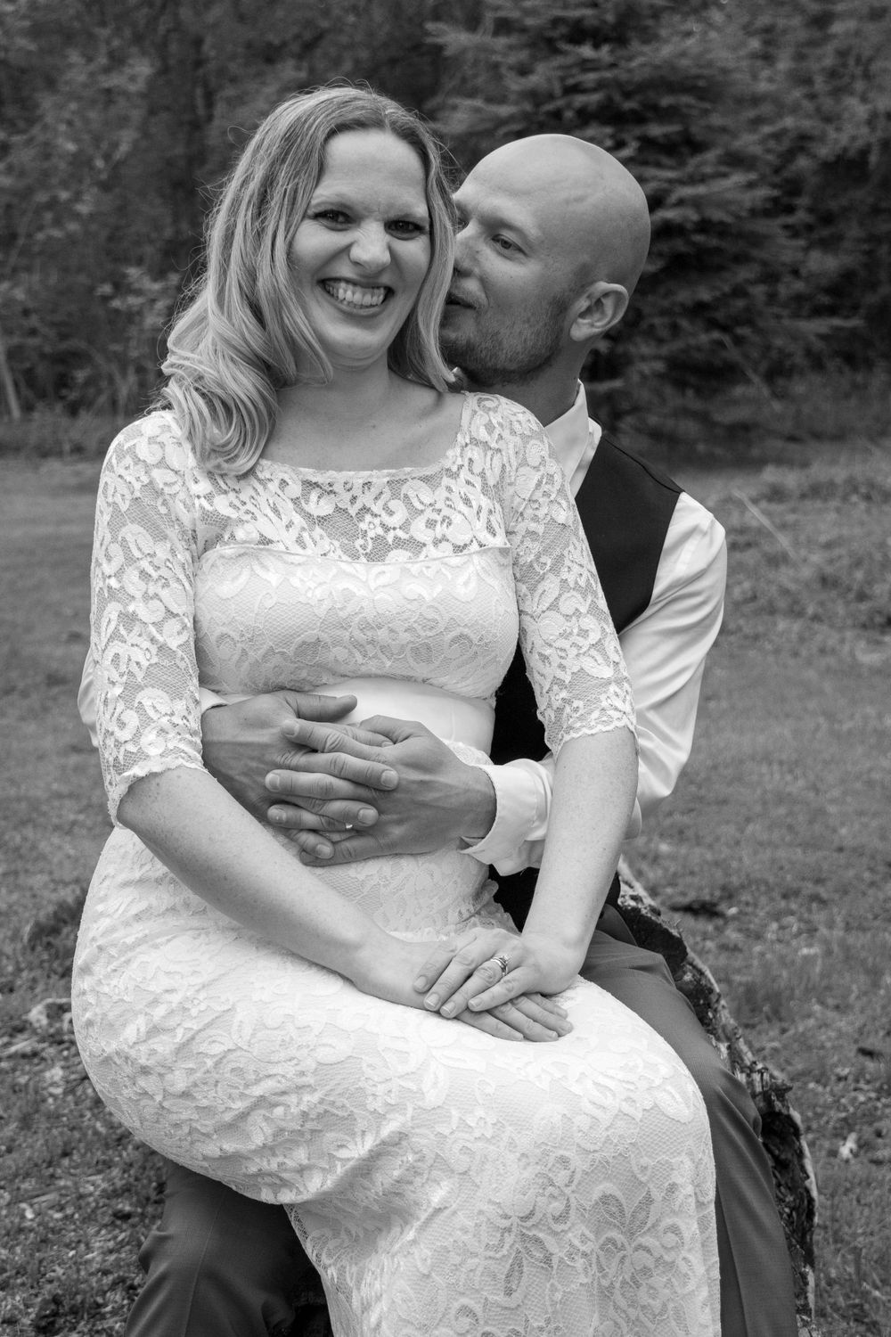 Bride sitting on groom's lap.  Groom telling bride a secret to make her laugh