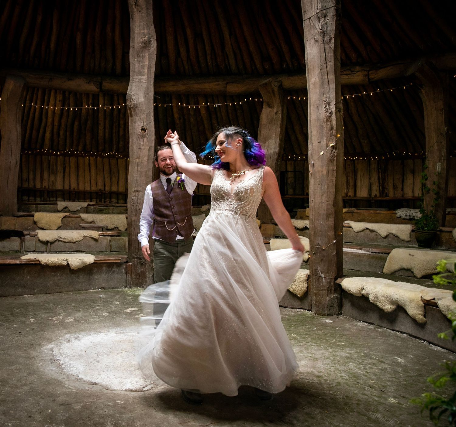 Wedding couple dancing and twirling in a rustic barn setting.