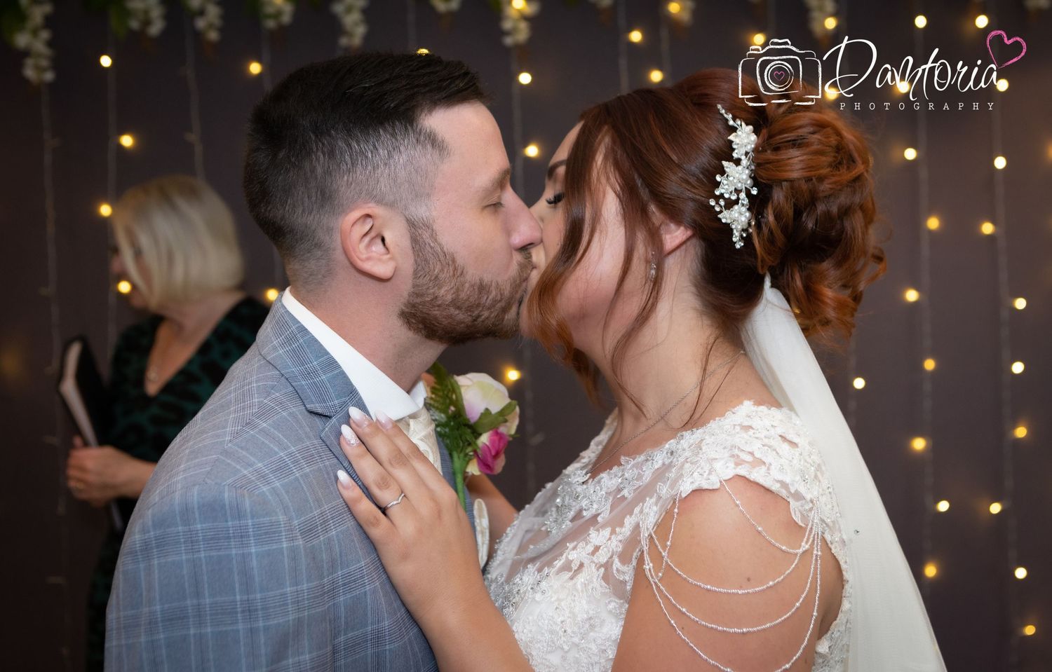 Couple shares intimate dance moment under warm string lights at wedding reception.