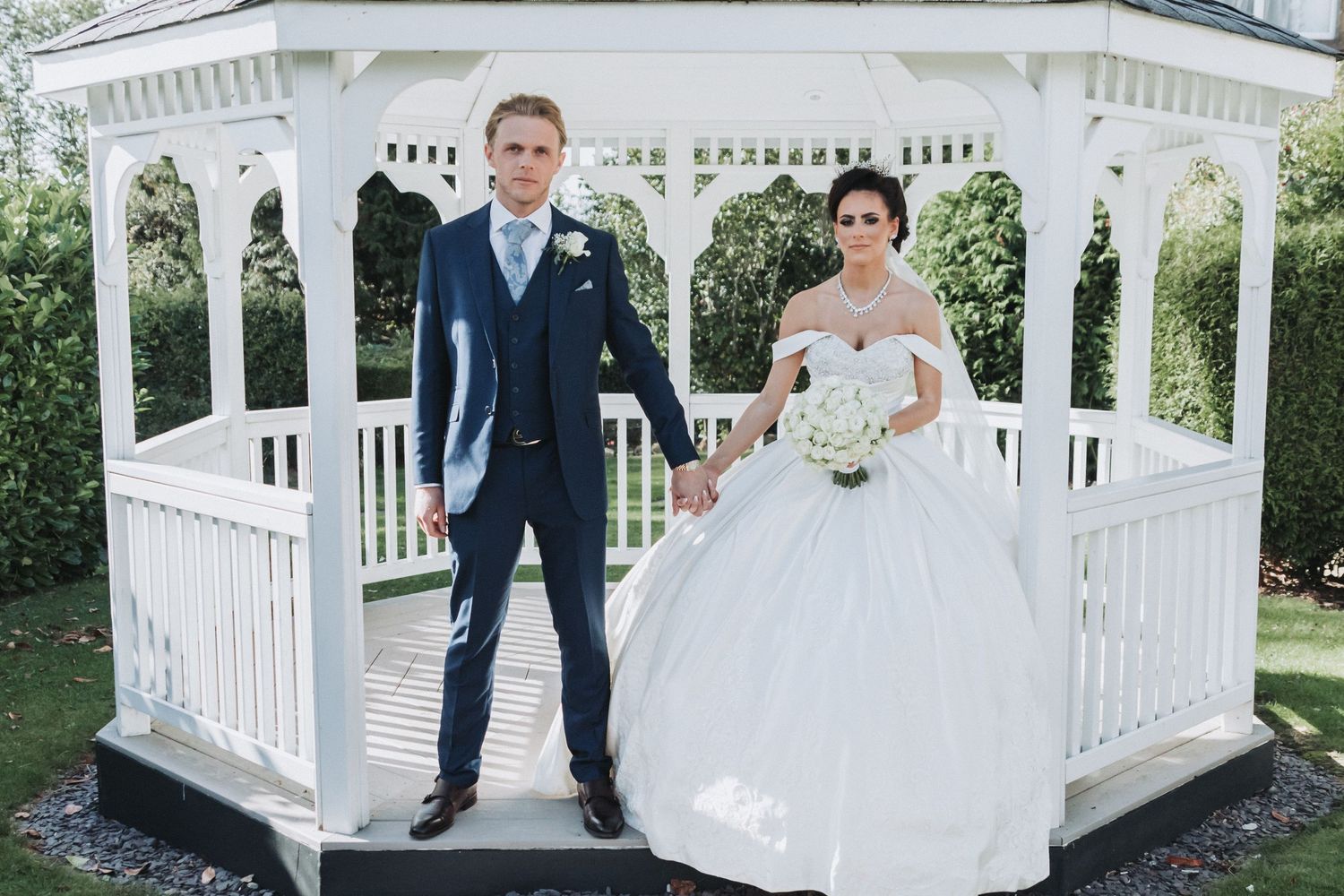 Bride and Groom holding hands looking at the camera under a pagoda