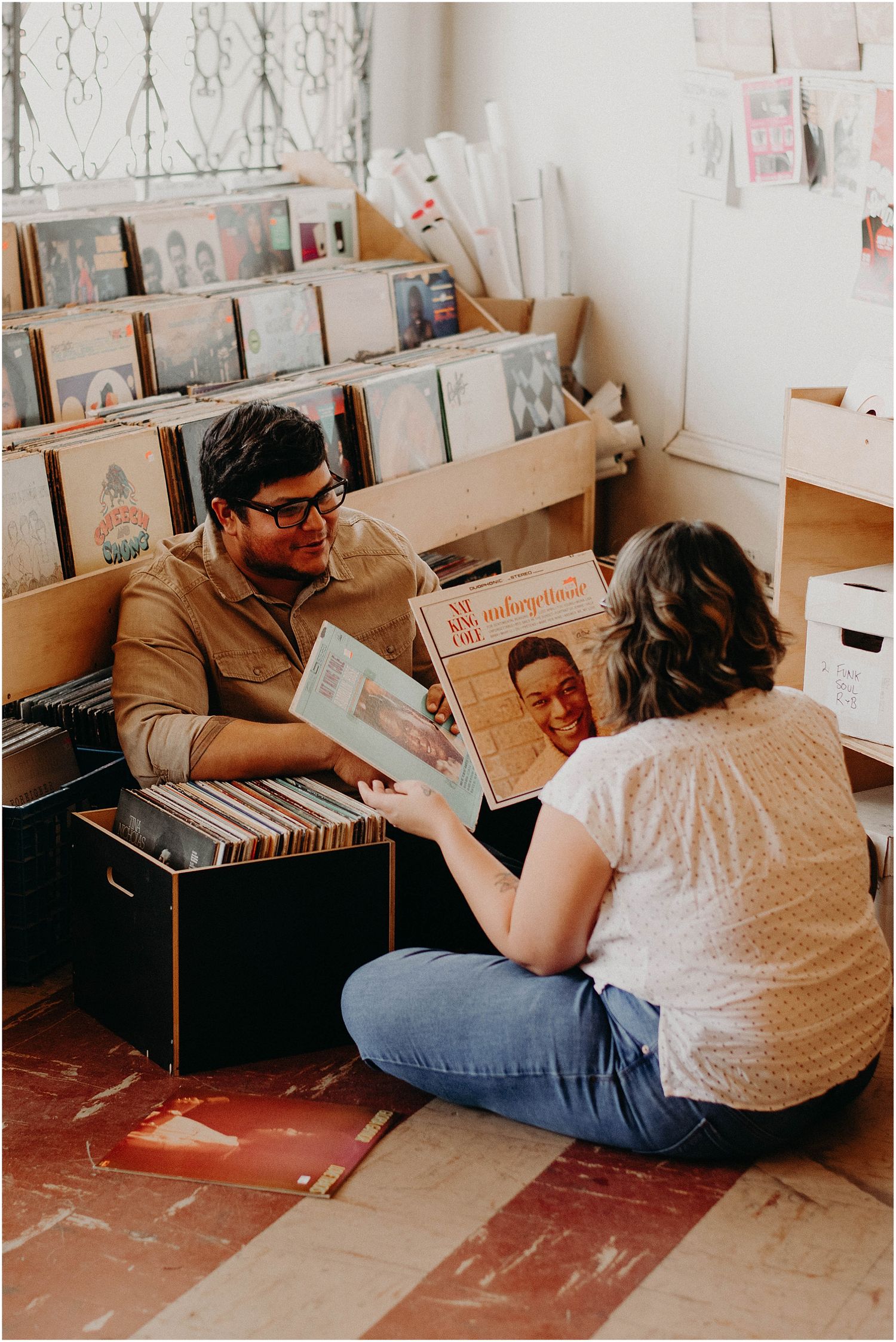 Two people share vintage records while sitting together at a local record shop.
