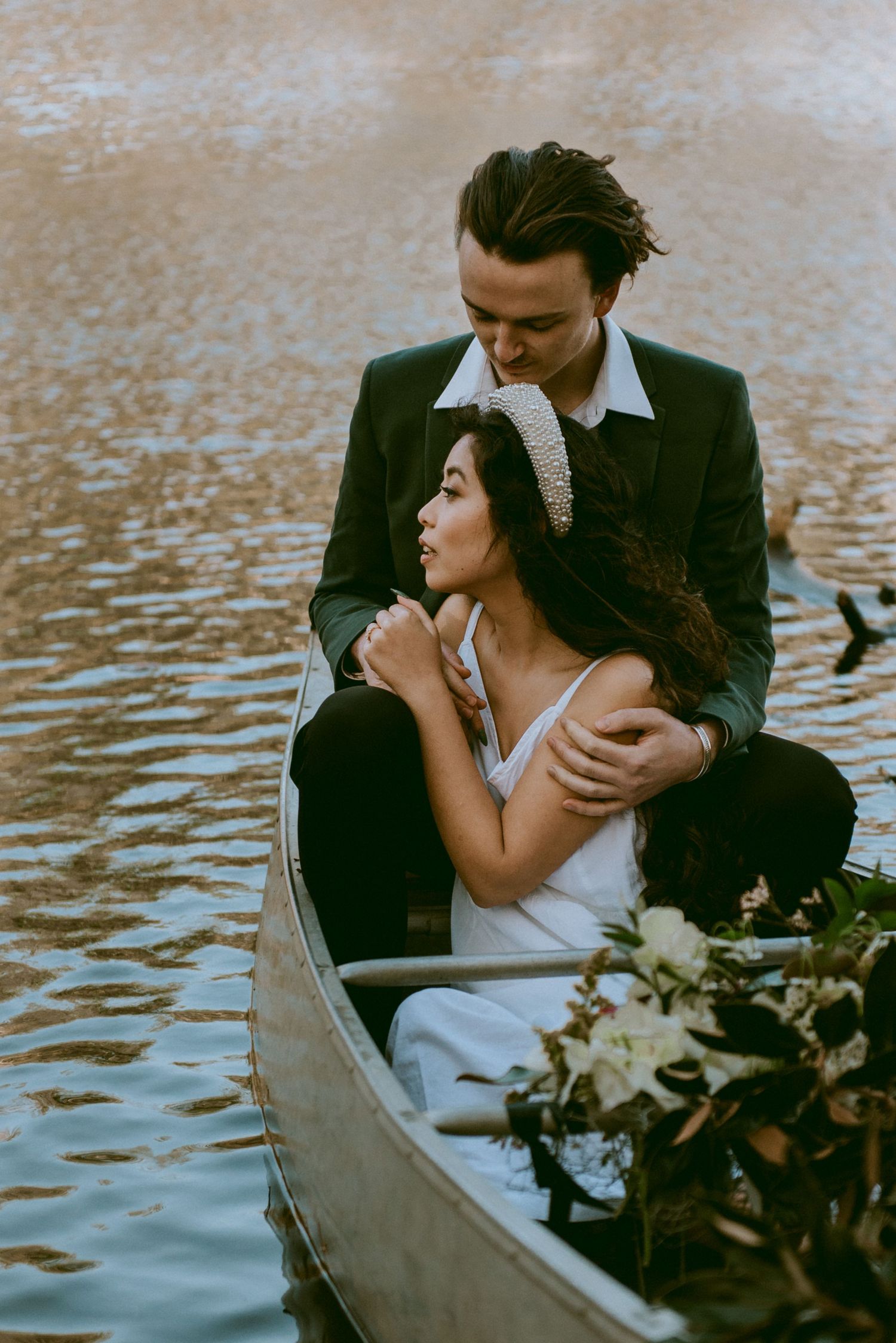 Bride and groom in a canoe in a lake looking out to the sunset