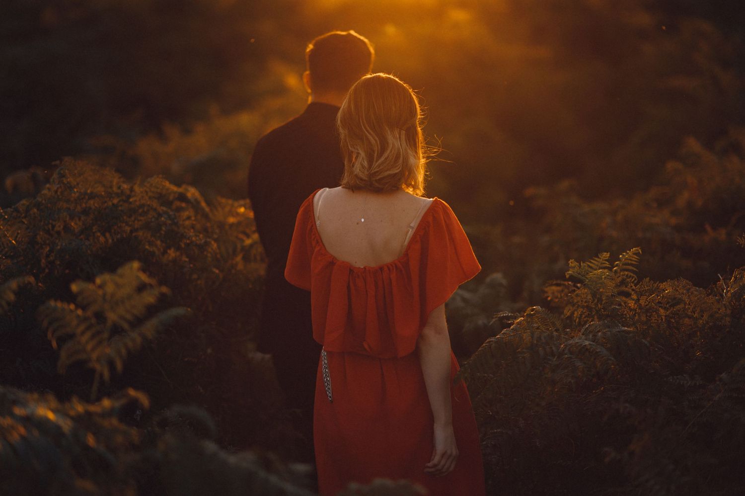 A couple standing together against a golden sunset backdrop.