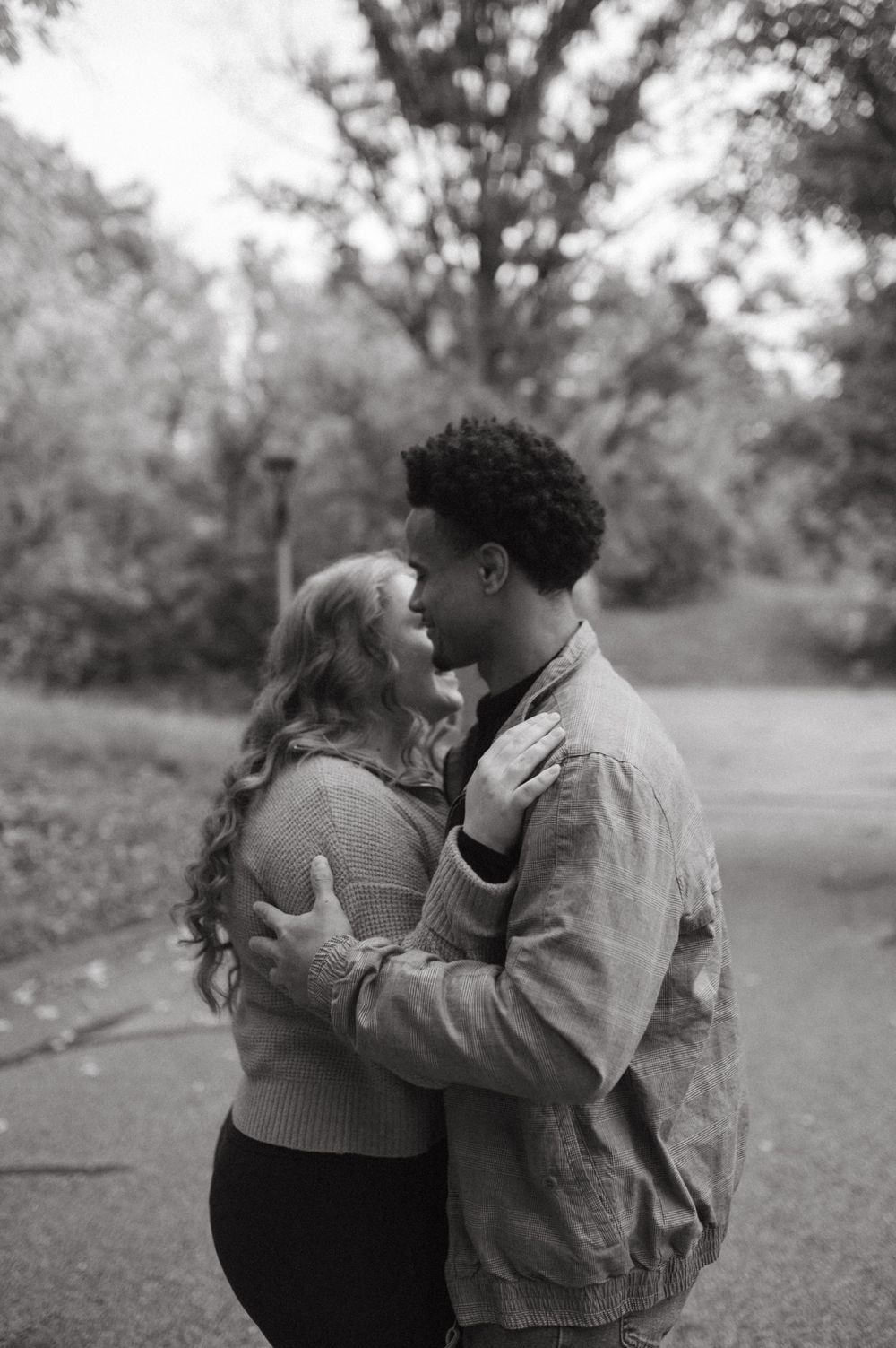 A romantic black and white moment between a couple on an autumn path.