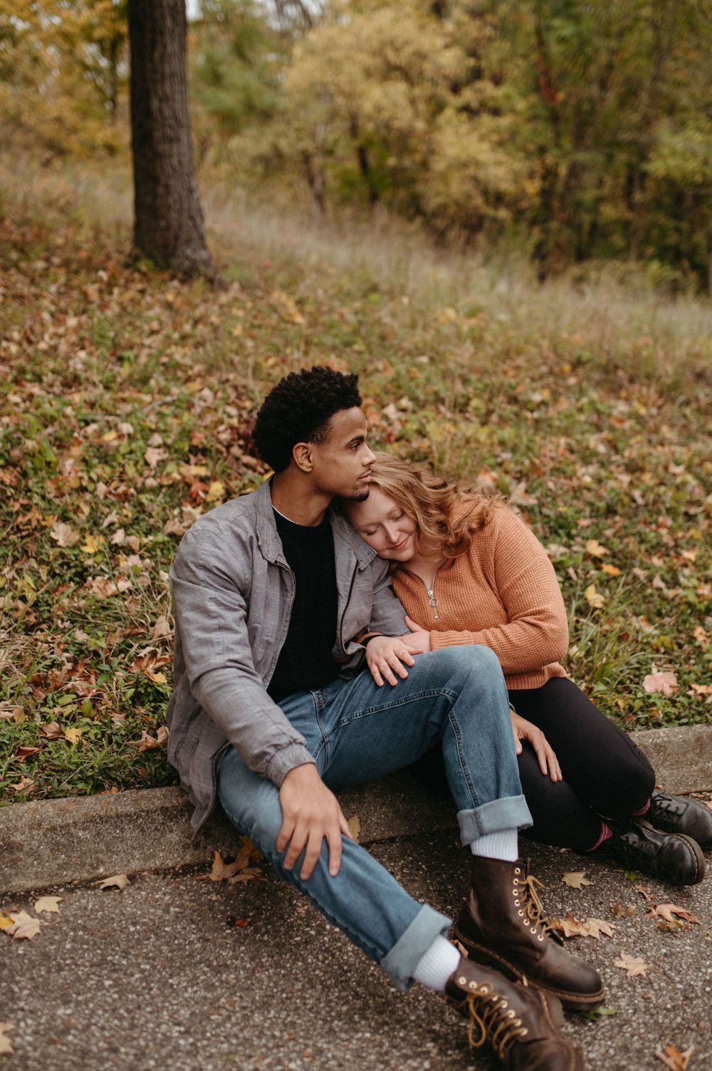 A couple relaxes on a curb during a romantic autumn afternoon.
