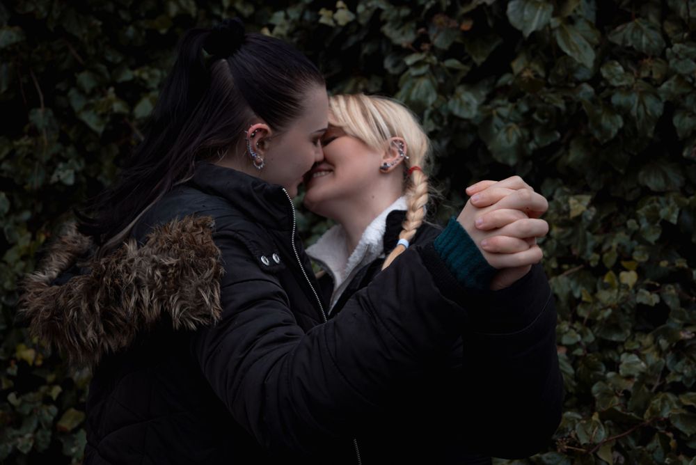 A romantic moment captured between two people in winter coats against an ivy backdrop.