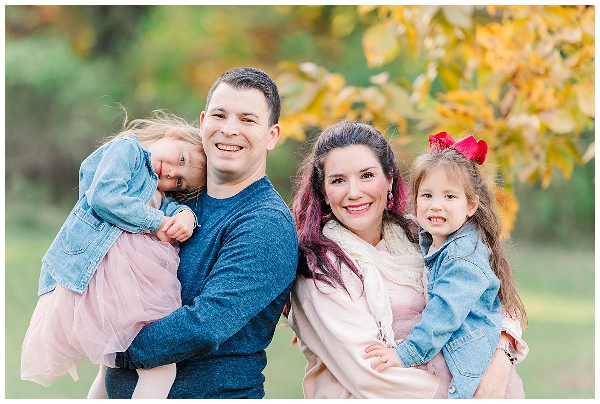 Family photographer captures sweet photo of mom dad and twin girls in autumn at Holliday Park Indianapolis Indiana