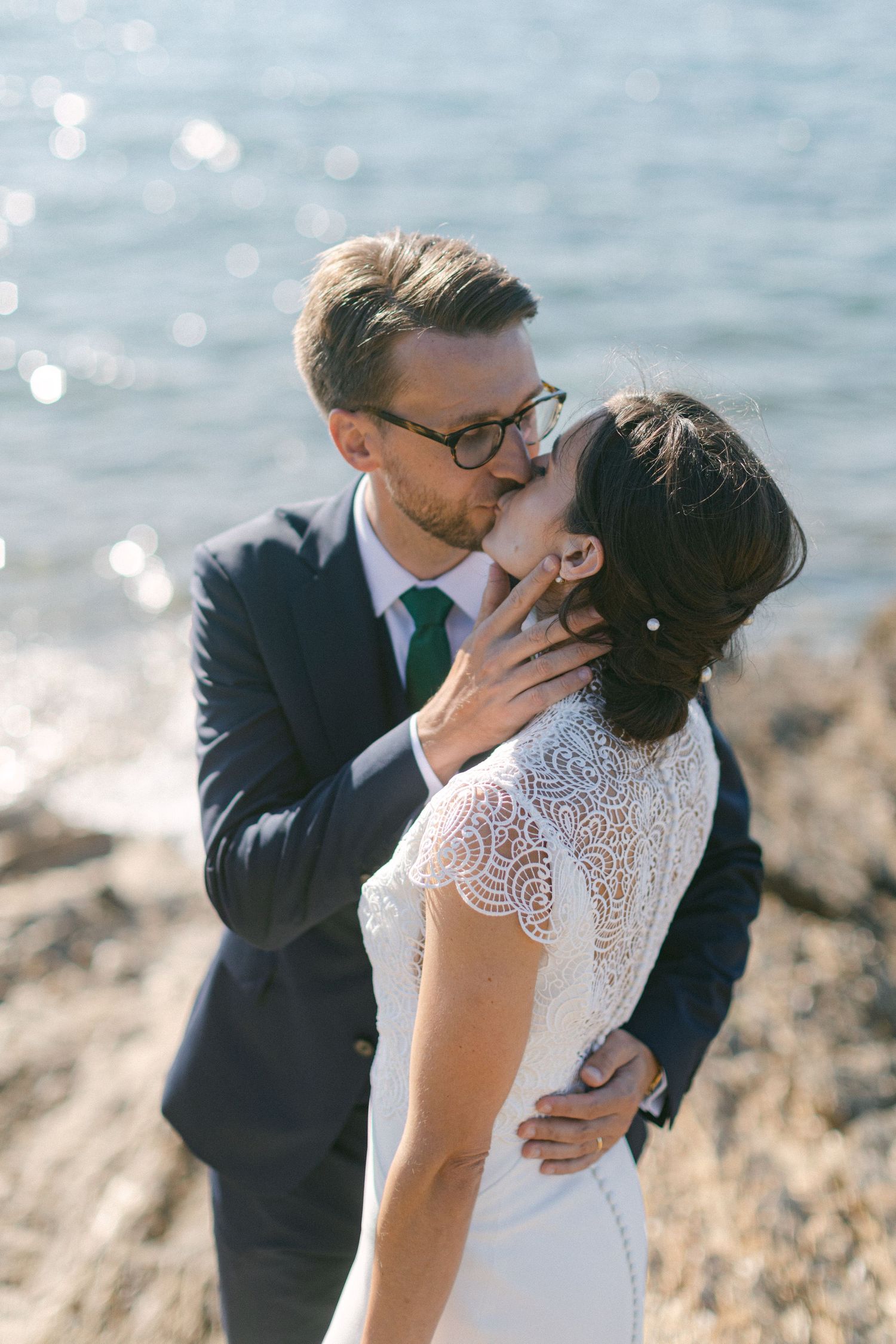 Des jeunes mariés échangeant un baiser romantique au bord de l’océan le jour de leur mariage.