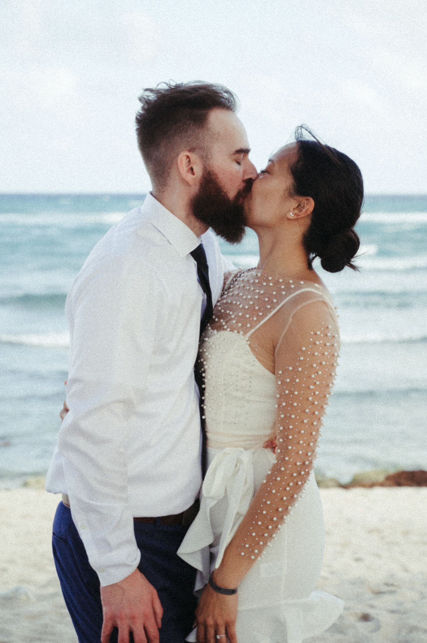 A romantic moment between a couple on a beach with ocean waves in the background.