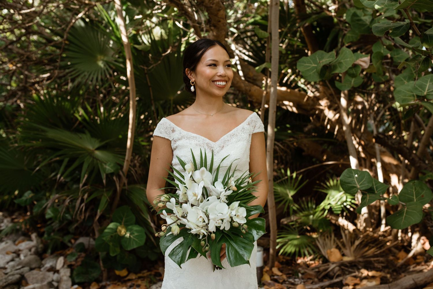 A wedding portrait featuring a white off-shoulder gown and tropical garden backdrop.