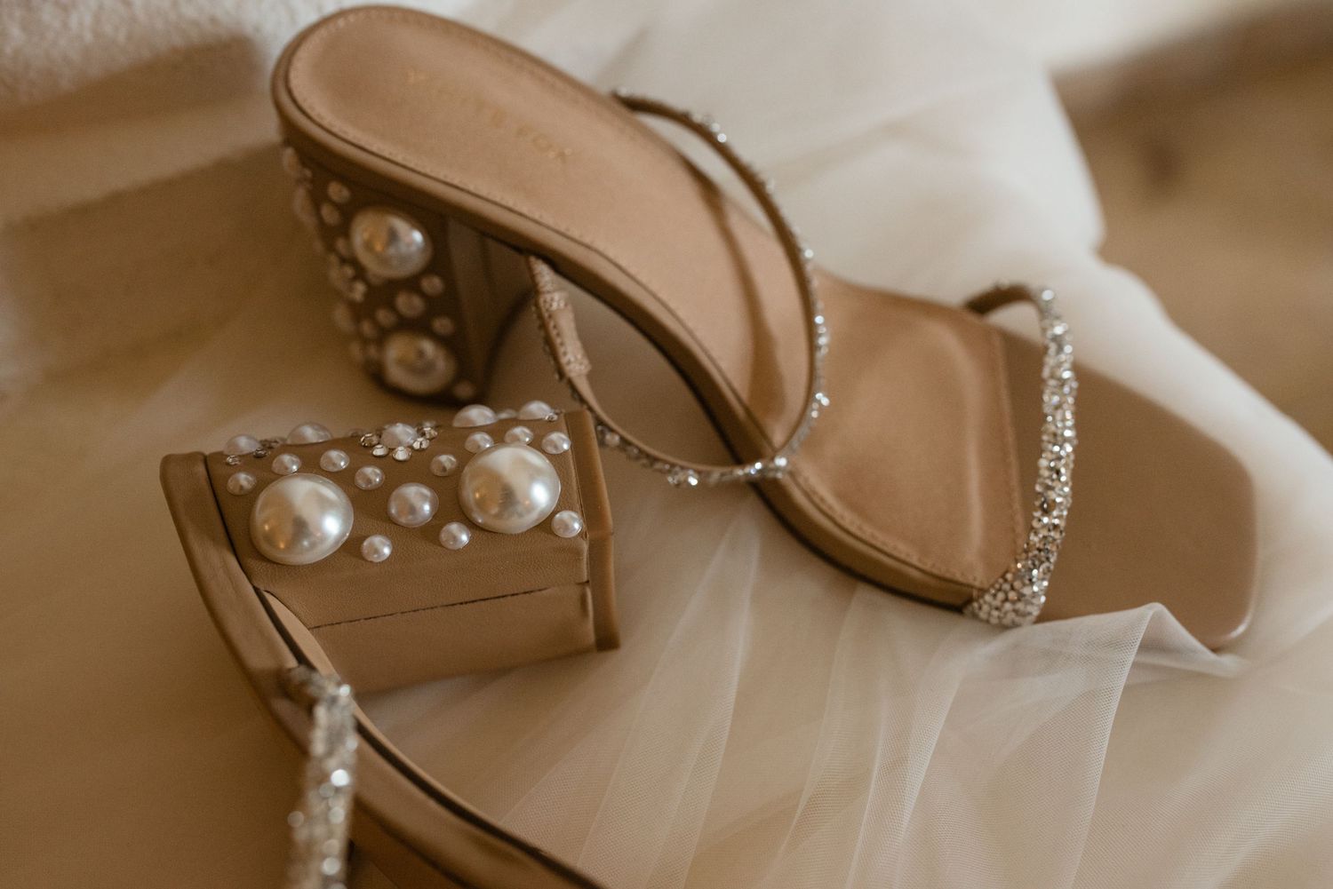 Designer bridal sandals with pearl details and sparkly straps captured in warm natural light.