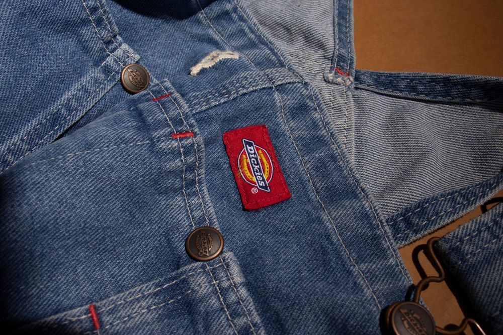 Close-up of denim jacket pocket with red branded patch detail.