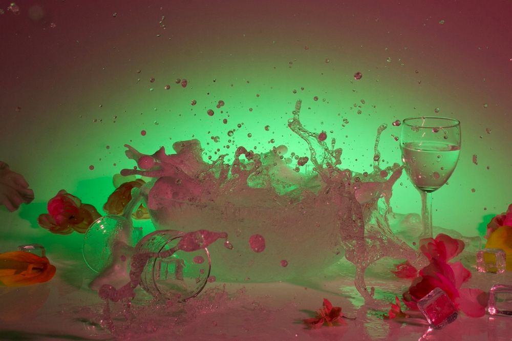 Abstract liquid art photography featuring red and green splashes with wine glass silhouettes.
