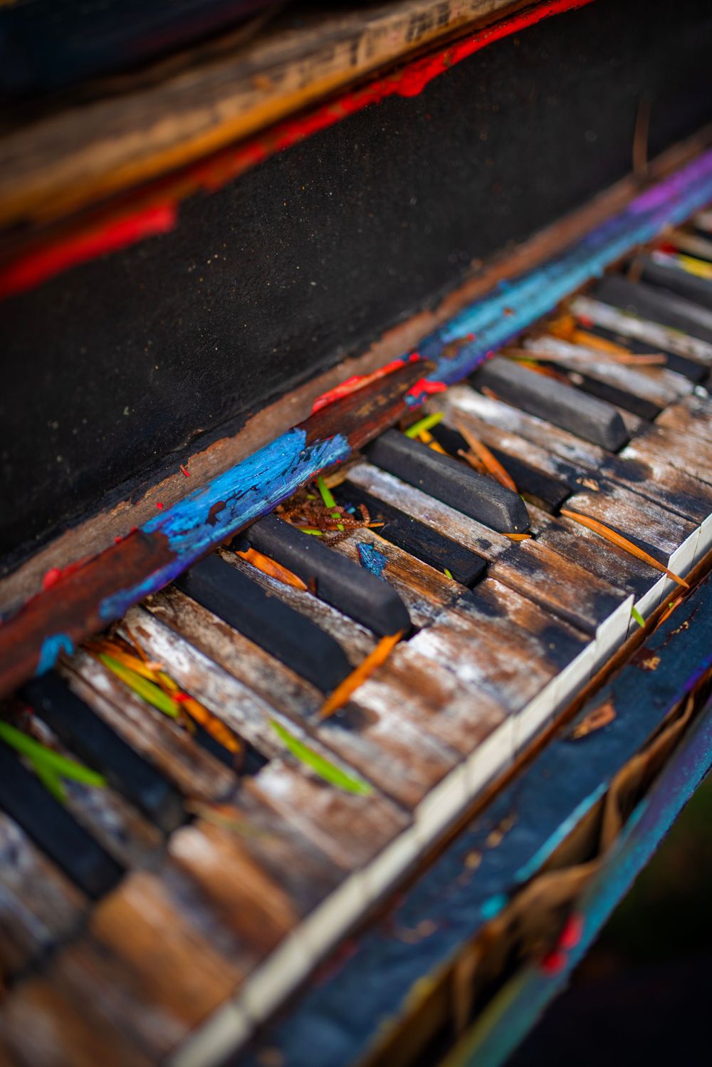 Close-up of weathered piano keys showing colorful paint and wear patterns.