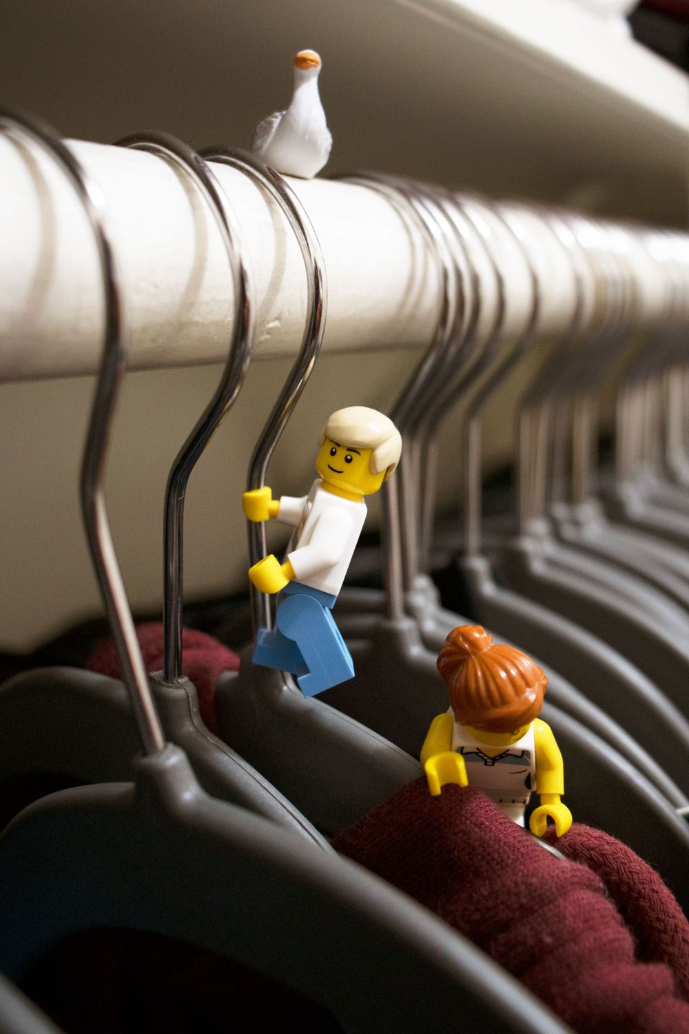 LEGO minifigures climbing on clothes hangers with a white seagull perched above.