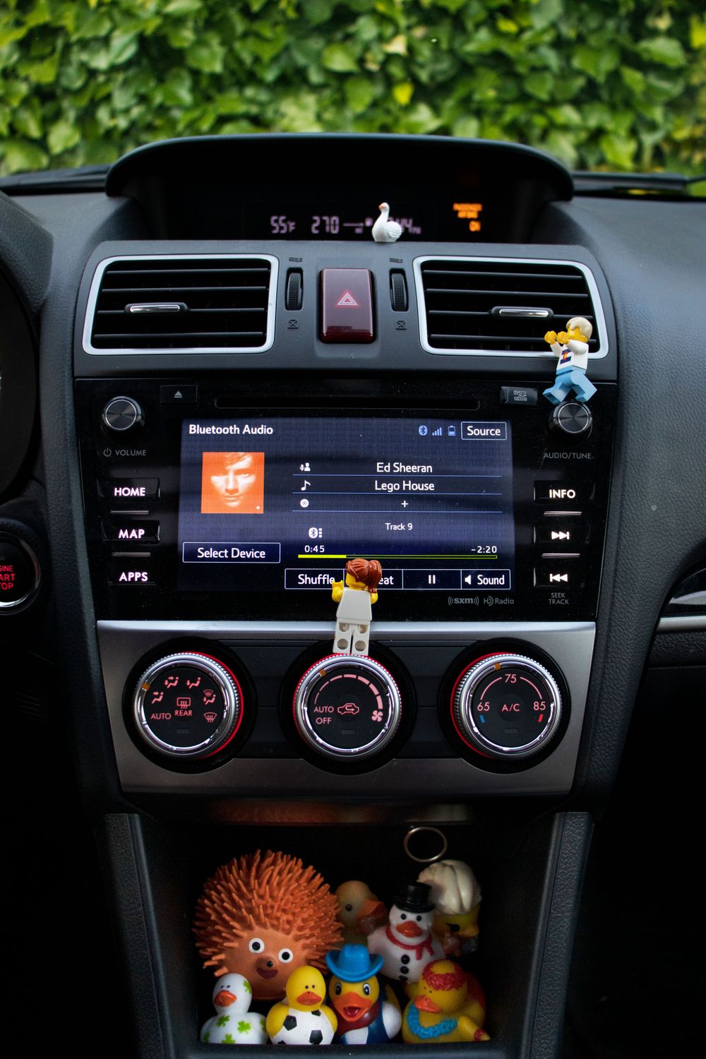 LEGO figures decorating a car dashboard with toys displayed in the console storage.