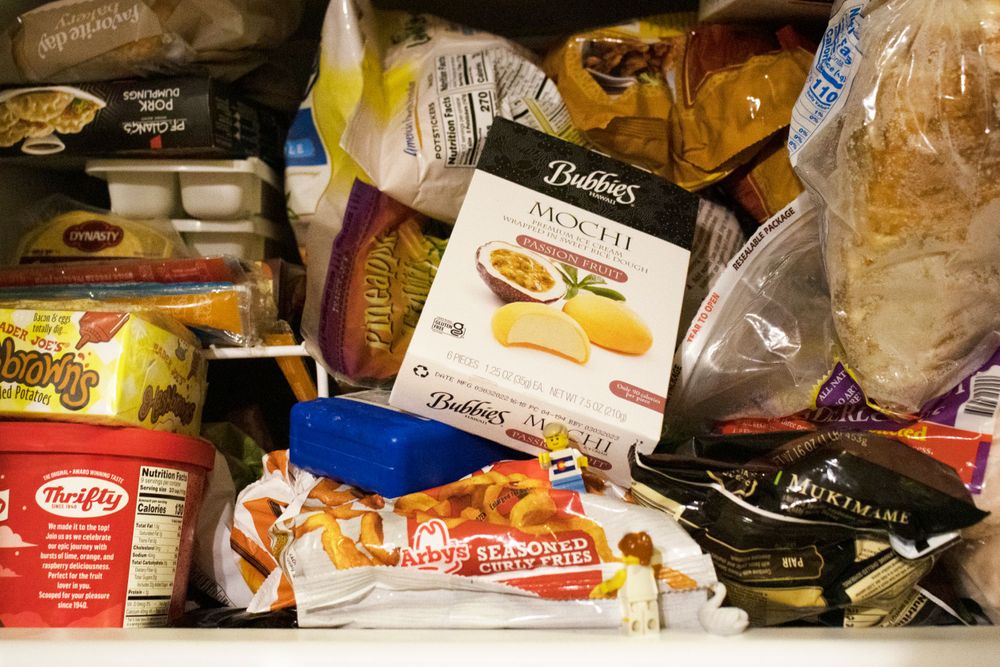 Assorted packaged food items and groceries stacked in a crowded freezer or storage space.