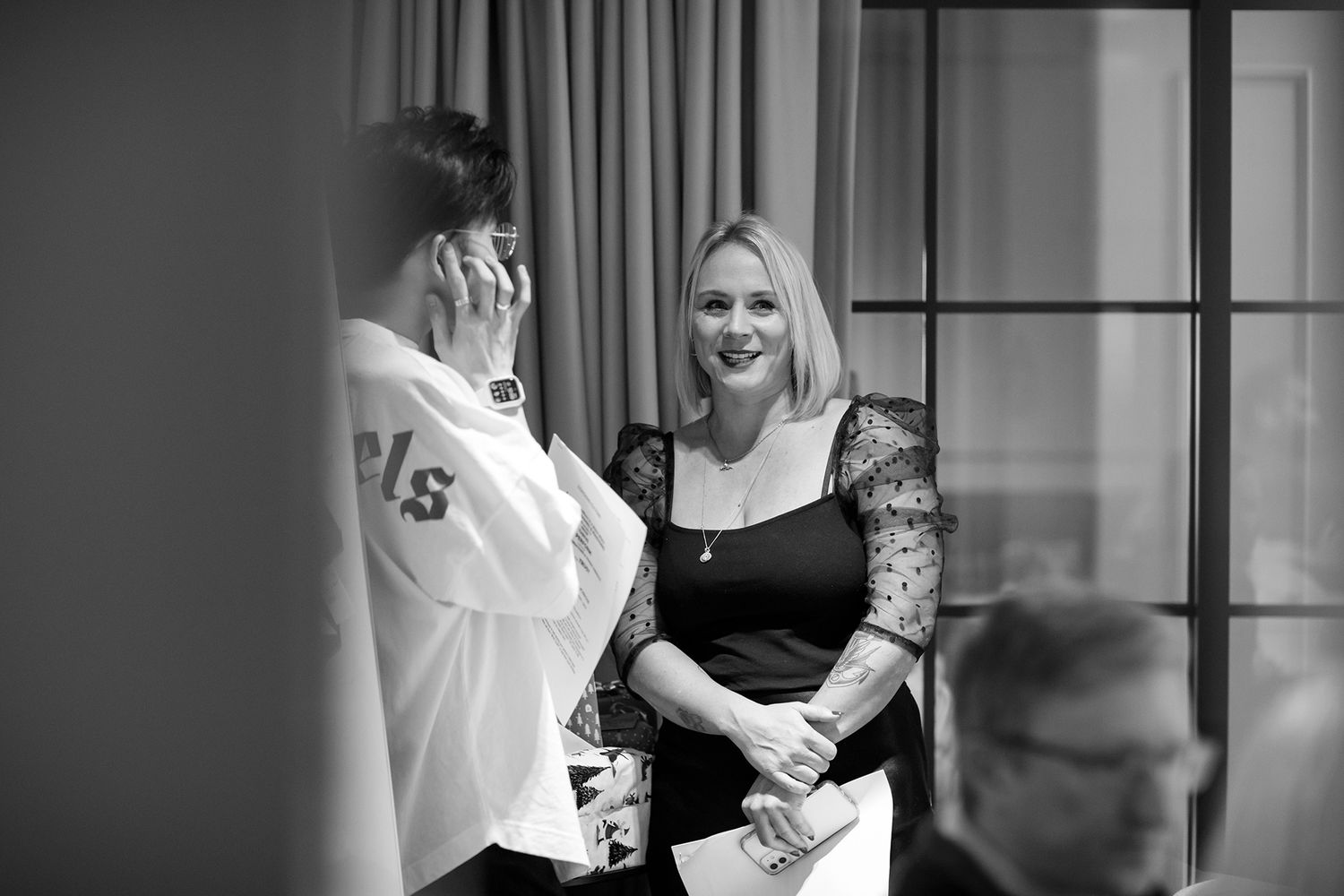 Black and white candid photo of people in conversation in an office setting during business branding photoshoot.