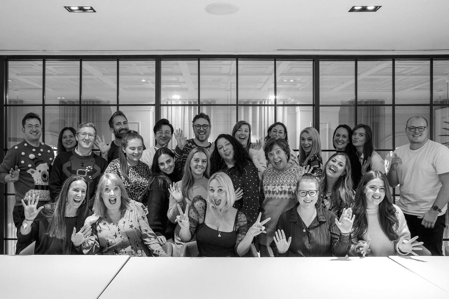 Large group photo of team members gathered together in modern office space during business branding photoshoot.