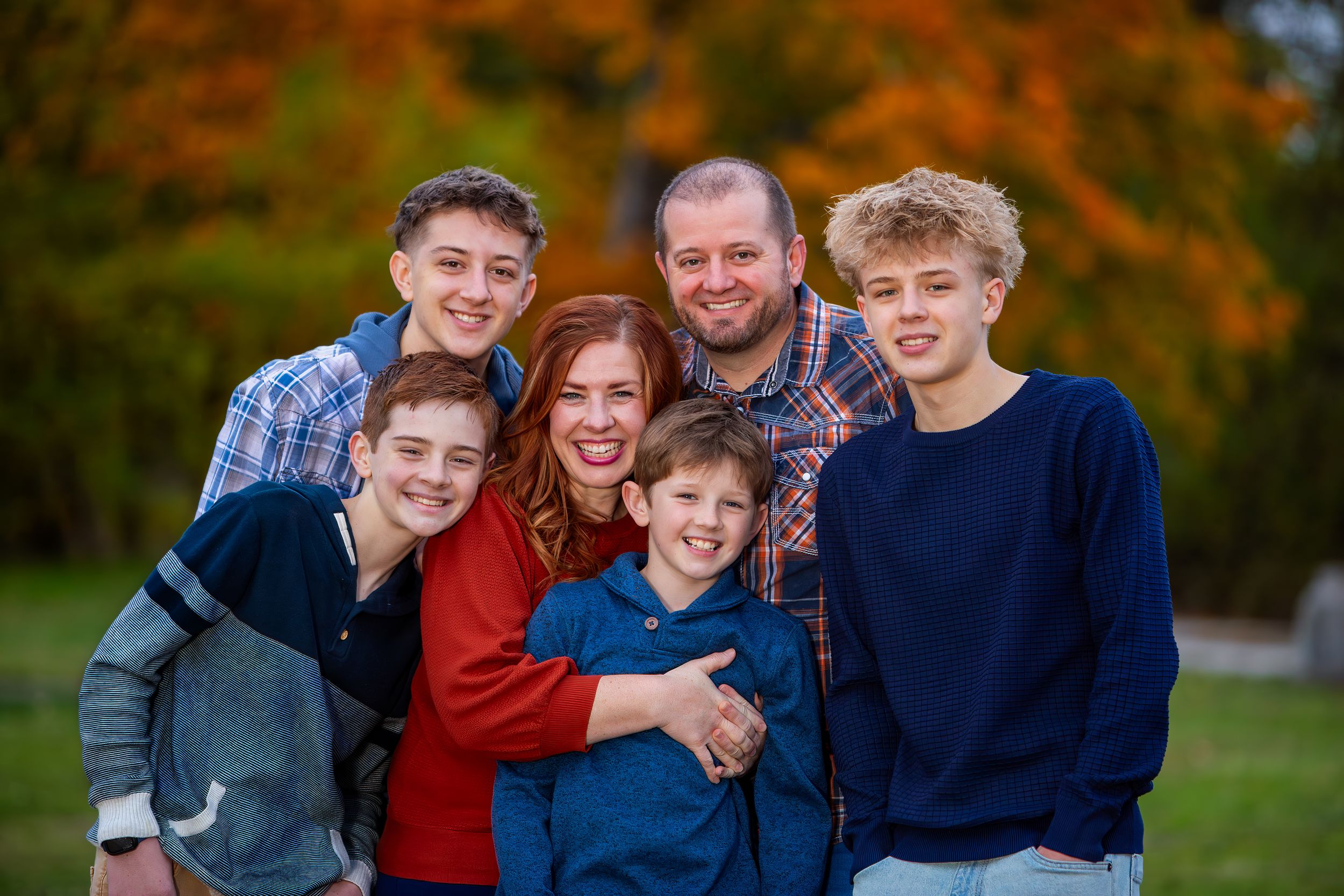 A series of candid family portraits captured outdoors against vibrant autumn foliage in warm natural lighting.