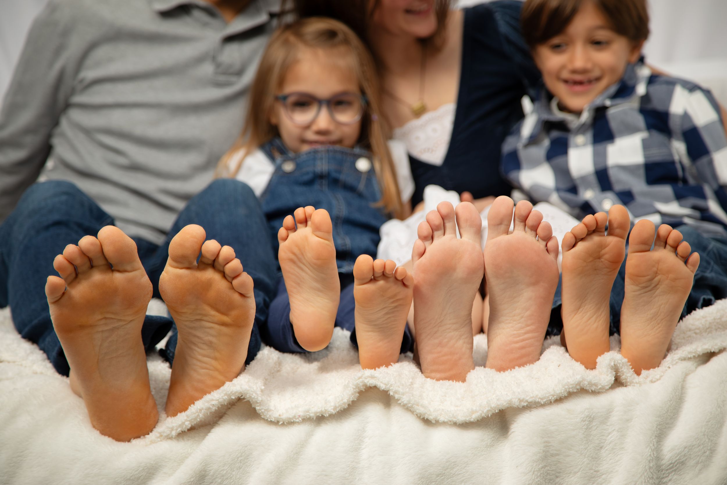 A row of bare feet lined up side by side on a light gray surface showing multiple people relaxing together.