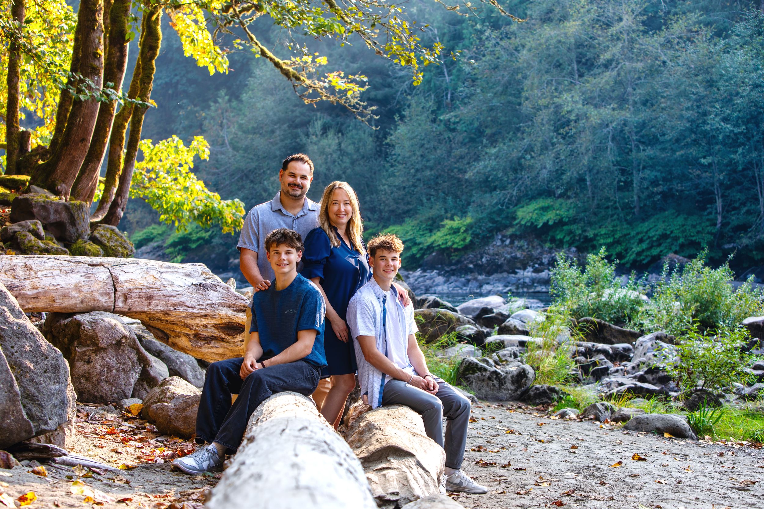 Hikers explore a scenic trail along a rocky creek surrounded by lush greenery and sunlit forest.